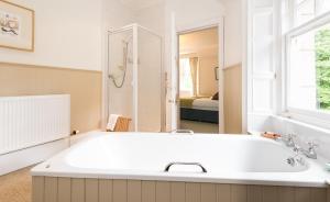baño blanco con bañera y ventana en Coig na Shee Guest House en Newtonmore