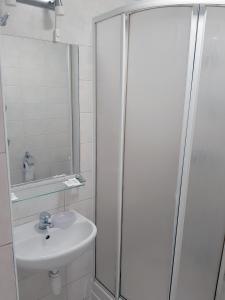 y baño blanco con lavabo y ducha. en Kambarių nuoma - Šiauliai SAURIDA, en Šiauliai