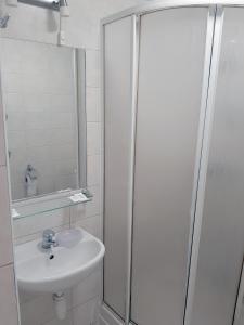een witte badkamer met een wastafel en een douche bij Kambarių nuoma - Šiauliai SAURIDA in Šiauliai