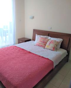 Bett mit rosa und weißer Bettwäsche und Kissen in der Unterkunft T&E Apartment in Larnaka