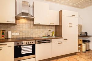 uma cozinha com armários brancos e um lavatório em Apartment Tuna em Sigmarszell