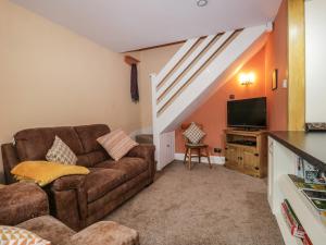 a living room with a couch and a television at Mount Pleasant Cottage in Grange Over Sands