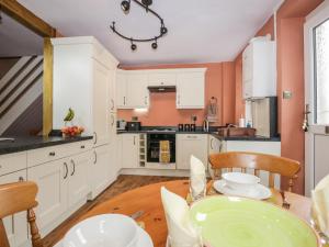 a kitchen with white cabinets and a table with chairs at Mount Pleasant Cottage in Grange Over Sands