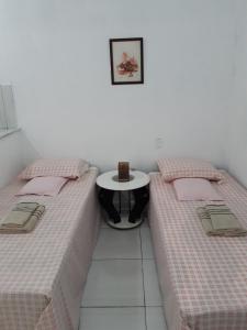 two beds in a room with a table between them at Kitnet Aconchegante Em Benfica in Rio de Janeiro