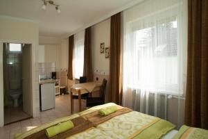 a bedroom with a bed and a kitchen and a window at Oleander Apartman in Hévíz