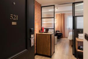 a room with a brick wall and a door with a desk at Golden Tulip Paris CDG Airport – Villepinte in Roissy-en-France
