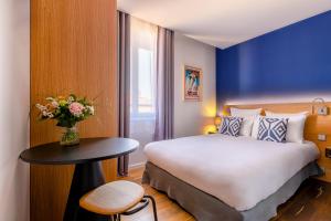 a bedroom with a bed and a table with a vase of flowers at Hotel Villa Koegui Biarritz in Biarritz