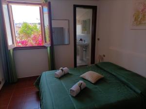 a bedroom with a green bed with two pillows on it at Ca' margo in Calasetta