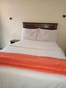 - un lit avec des draps et des oreillers orange et blancs dans l'établissement Lucy Guest House (B&B), à Addis-Abeba