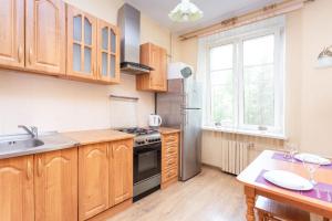 cocina con armarios de madera y nevera de acero inoxidable en Studiominsk Apartments, en Minsk