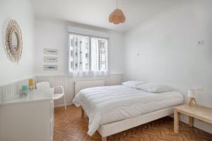 a white bedroom with a bed and a table at Votre cocon à proximité de la plage de La Baule in La Baule