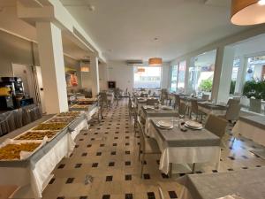 un restaurante con mesas y sillas con comida. en Hotel Lux, en Gabicce Mare