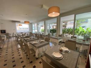 a dining room with tables and chairs and windows at Hotel Lux in Gabicce Mare