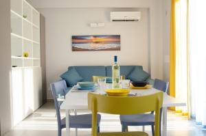 Solemare Casa Vacanze في كاستيلاماري ديل غولفو: غرفة طعام مع طاولة بيضاء وكراسي صفراء