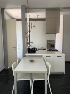 Mery's House casa vacanza في فانو: مطبخ أبيض مع طاولة بيضاء وكراسي