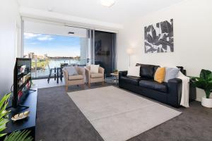 布里斯班Amazing River View - 3 Bedroom Apartment - Brisbane CBD - Netflix - Fast Wifi - Carpark的一间带黑色沙发的客厅和一间带阳台的客厅