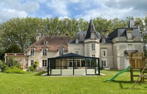 a large house with a playground in front of it at Château l'Hubertière, classé du tourisme 4 étoiles in Bouresse