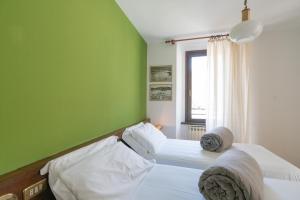 two beds in a room with a green wall at Hotel Posta in Aprica