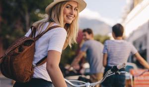 a woman wearing a hat is standing with a bike at Motel L Hammarby Sjöstad in Stockholm