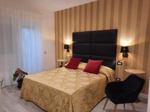 ein Schlafzimmer mit einem Bett mit roten Kissen und einem Stuhl in der Unterkunft MARITZA S HOUSE IN ROME in Rom