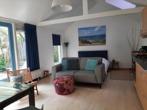 uma sala de estar com um sofá e uma mesa em Boshuisje Petten aan Zee em Petten