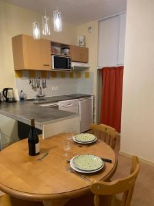 una cocina con una mesa de madera con platos y copas de vino en Résidence Grand Hôtel Appartement Standing, en Aulus-les-Bains