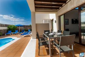 un patio con mesa y sillas y una piscina en 3-Bed Villa on Private Complex with Tennis Court, en Playa Blanca