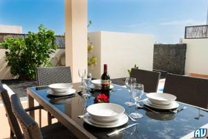 una mesa con copas y una botella de vino en el patio en 3-Bed Villa on Private Complex with Tennis Court, en Playa Blanca