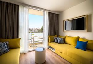 a living room with a yellow couch and a tv at Valamar Parentino Hotel in Poreč