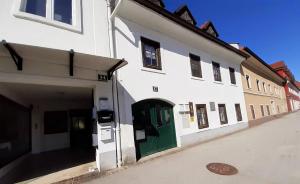 a white building with a green door on a street at Fassbinder Klause mit Mini-Terrasse in Sankt Veit an der Glan