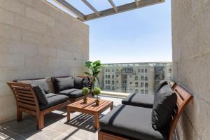 einen Balkon mit einem Sofa und Stühlen sowie einem großen Fenster in der Unterkunft Harav agan - New building in the Center in Jerusalem