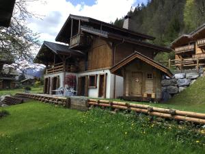 uma casa de madeira com um relvado verde em frente em CHALET MITCH em Morzine