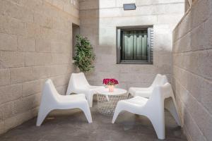 un patio con sillas blancas, una mesa y una ventana en Harav agan - 9 people - Full Option, en Jerusalén