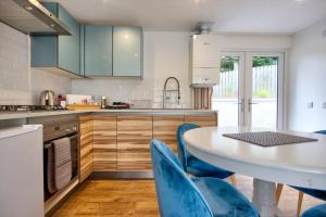 uma cozinha com uma mesa branca e cadeiras azuis em Charming 1-Bed Cottage in Inverness em Inverness