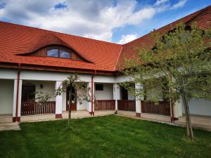 a house with a red roof and a yard at Szabolcs Vezér Panzió in Szabolcs