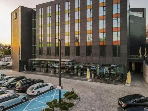 ibis Styles Lublin Stare Miasto في لوبلين: موقف للسيارات مع وقوف السيارات أمام المبنى