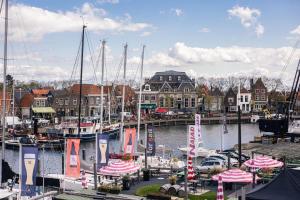 een groep boten aangemeerd in een jachthaven met gebouwen bij Hotel Snouck van Loosen in Enkhuizen