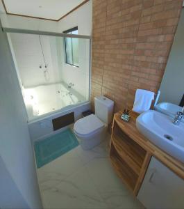 a bathroom with a toilet and a sink and a tub at Stolz Chales in Guarda do Embaú