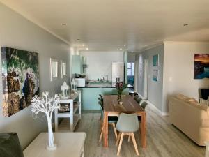 kuchnia i salon ze stołem i kanapą w obiekcie Sage at Whale Cove - Sea Facing Apartment w mieście De Kelders