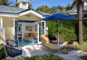 a patio with chairs and a blue umbrella at The Breakers Palm Beach in Palm Beach