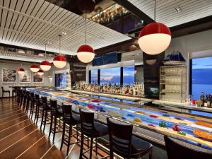 a bar with a long counter with chairs and lights at The Breakers Palm Beach in Palm Beach +34 photos