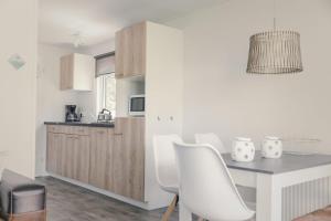 a kitchen with a dining table and white chairs at Groepsaccommodatie - 6x bungalette 5p met veranda in Zuna