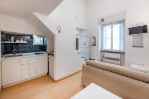 una cocina con armarios blancos y un sofá en una habitación en Le Casasse "Vico Mendaro 8", en Varigotti
