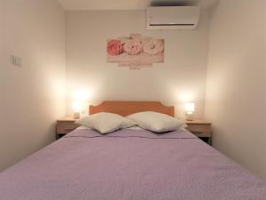 ein Schlafzimmer mit einem lila Bett und zwei Kissen in der Unterkunft Apartmani Divić in Drvenik