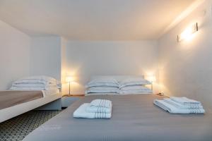 una camera bianca con due letti e asciugamani di Le Casasse "Vico Mendaro 10" a Varigotti