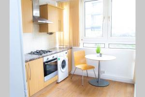 cocina con mesa y lavadora en Shoreditch Hoxton Large 3 Bed Garden Flat FREE PARKING AOR ONLY, en Londres