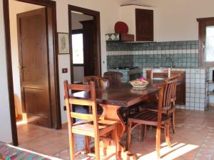 a kitchen with a wooden table and wooden chairs at d Pietraia 11B Trilo in Badesi