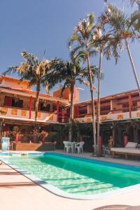 una piscina frente a un hotel con palmeras en Hotel Ferrugem Eco Village, en Garopaba