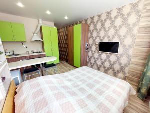 a bedroom with a bed and a kitchen with green cabinets at Апартаменты СВ "Атлант" 2 in Tver