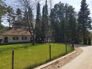 a fence in front of a house with a yard at SunStone Apartment in Zlatibor